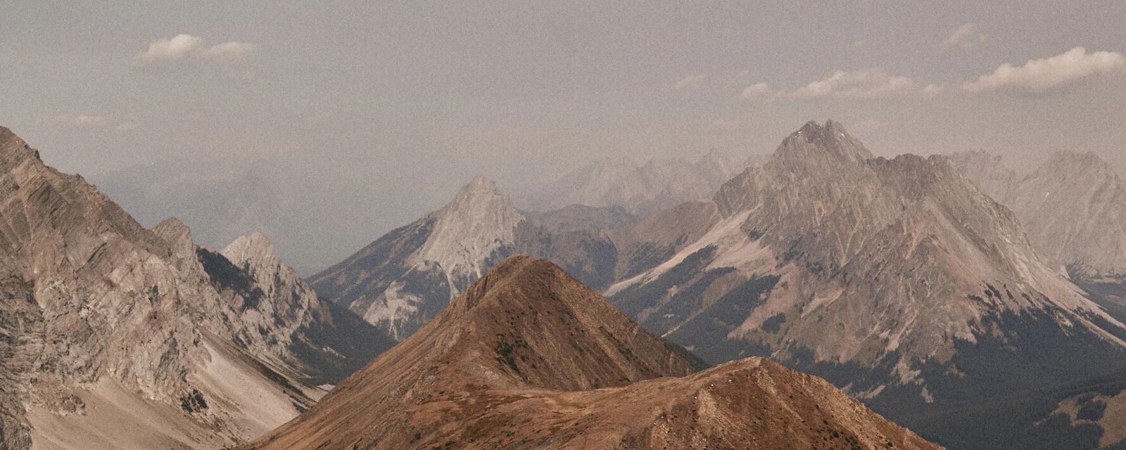 Smoke-hazed mountain ridgelines receding into a dim sky